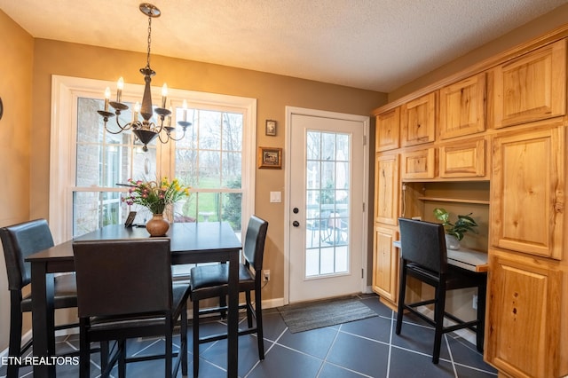 dining room with baseboards, a chandelier, a textured ceiling, and dark tile patterned flooring