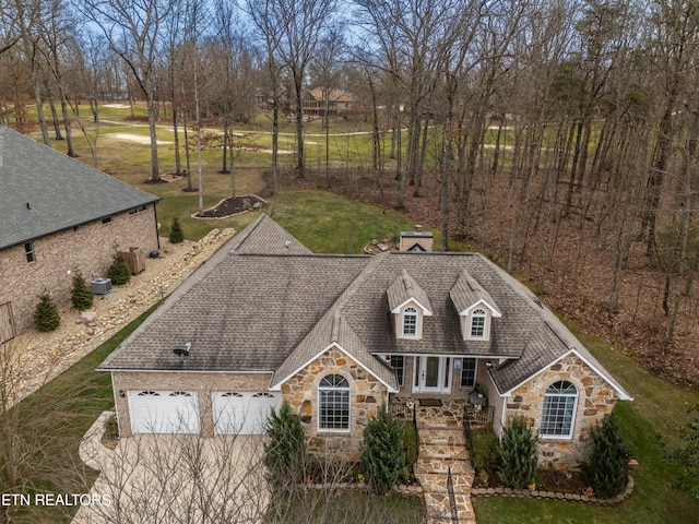 view of front of property with cooling unit, a garage, a shingled roof, stone siding, and a chimney