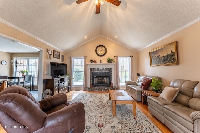 living room featuring light wood-style floors, a healthy amount of sunlight, vaulted ceiling, and ornamental molding