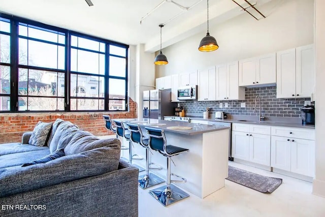 kitchen featuring a sink, tasteful backsplash, a kitchen breakfast bar, stainless steel appliances, and white cabinets