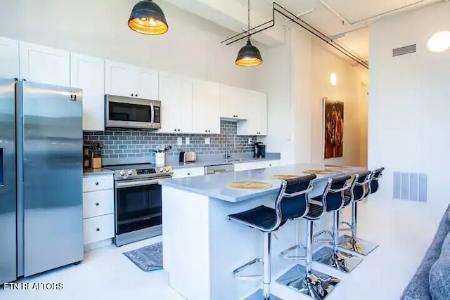 kitchen featuring backsplash, white cabinets, stainless steel appliances, and visible vents