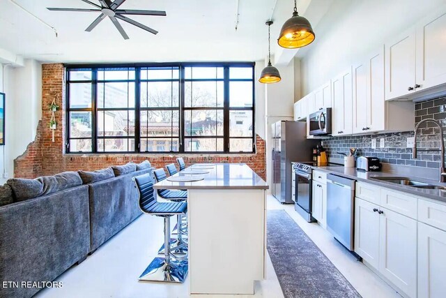 kitchen featuring stainless steel appliances, backsplash, a sink, white cabinets, and a ceiling fan