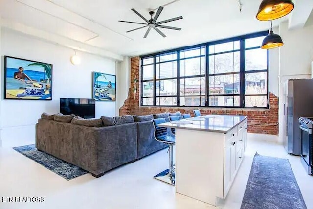 living room featuring a ceiling fan, plenty of natural light, and brick wall