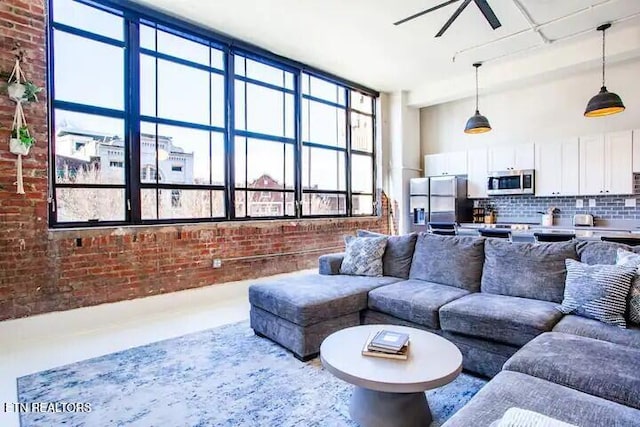 living room featuring a ceiling fan and brick wall