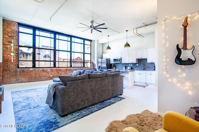living room with a ceiling fan, concrete flooring, and brick wall