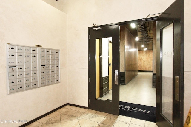 hall with baseboards, a high ceiling, and mail area