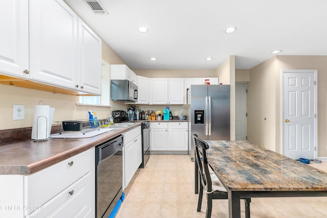 kitchen with recessed lighting, white cabinetry, visible vents, light floors, and black appliances