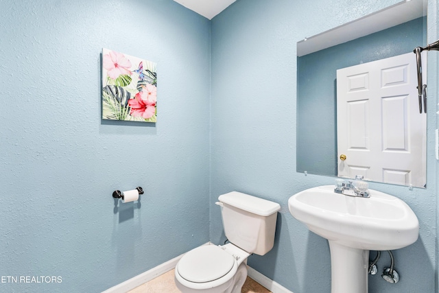 half bathroom featuring baseboards and toilet