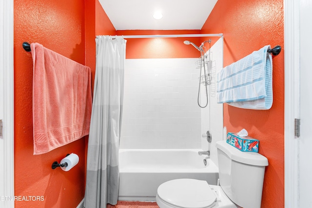 bathroom with toilet, shower / tub combo, and a textured wall