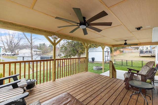 wooden deck with an outbuilding, a yard, a shed, and ceiling fan