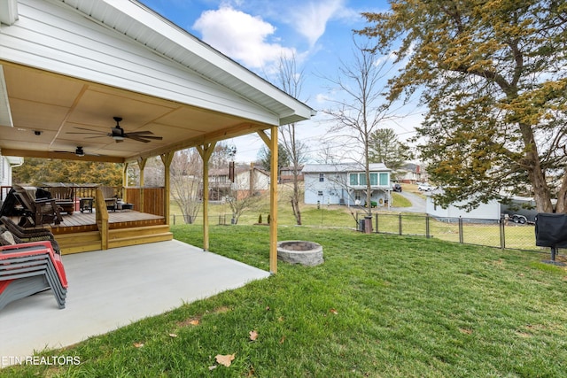 view of yard with a fire pit, ceiling fan, fence, a deck, and a patio area