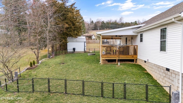 view of yard with a storage unit, fence, an outdoor structure, a wooden deck, and central AC unit