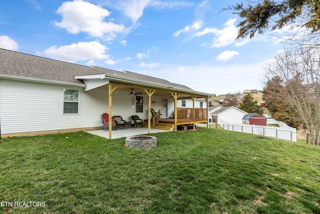 rear view of house with ceiling fan, fence, an outdoor fire pit, a lawn, and a patio