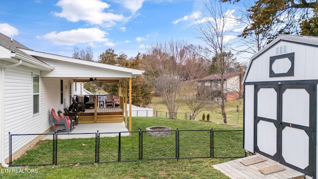 view of yard featuring ceiling fan, a fenced backyard, an outbuilding, a storage unit, and a gate