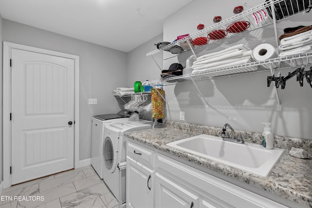 clothes washing area featuring marble finish floor, independent washer and dryer, a sink, cabinet space, and baseboards