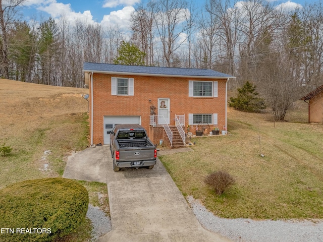 bi-level home featuring brick siding, concrete driveway, a garage, and a front yard