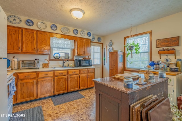 kitchen featuring a sink, light countertops, black microwave, a textured ceiling, and brown cabinets