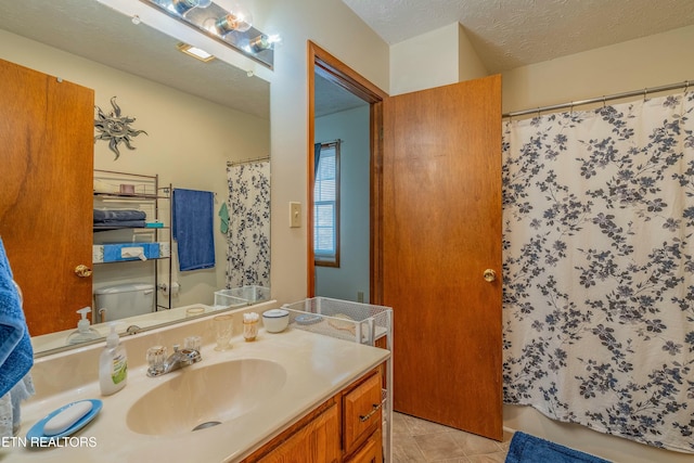 bathroom featuring toilet, curtained shower, a textured ceiling, tile patterned flooring, and vanity