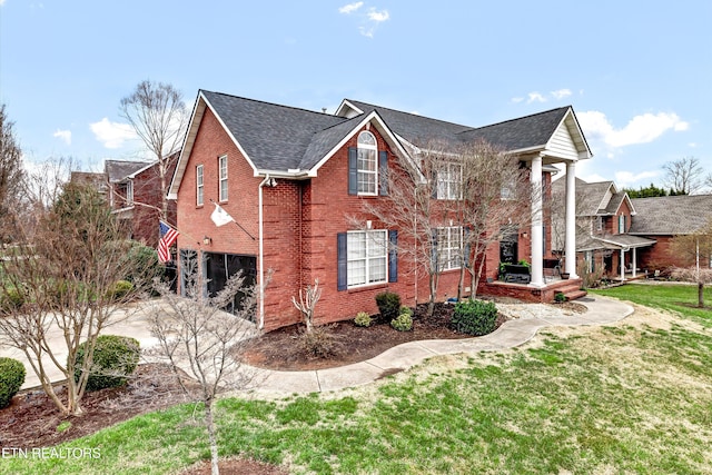 view of front facade featuring brick siding and a front yard