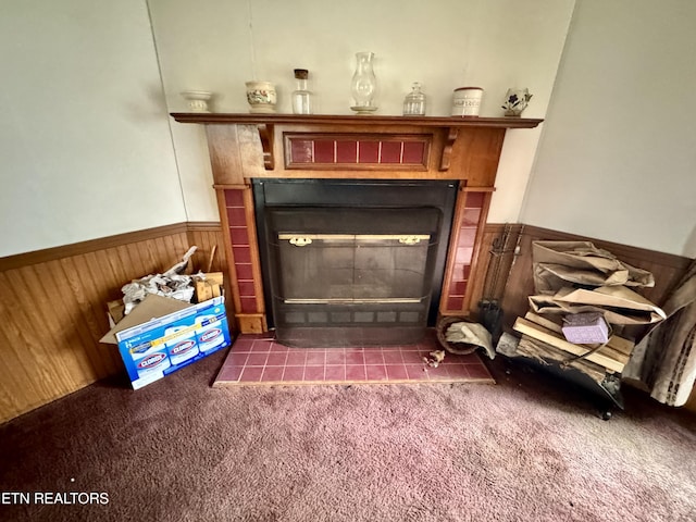 room details with a wainscoted wall, wood walls, carpet, and a tile fireplace