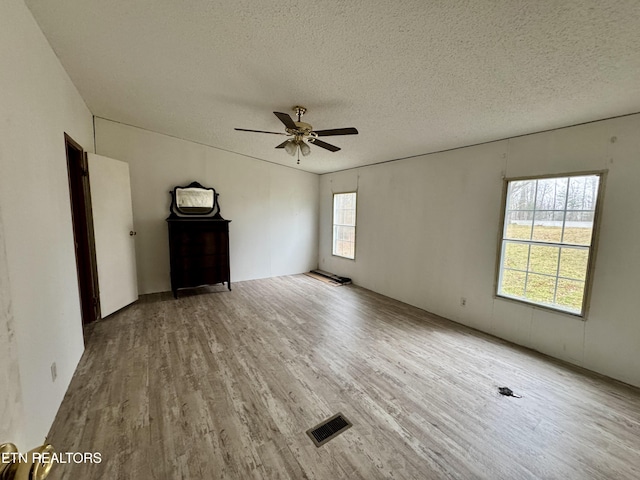 empty room featuring a textured ceiling, visible vents, and wood finished floors