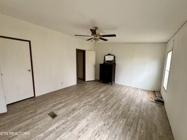 interior space featuring visible vents, ceiling fan, a textured ceiling, and wood finished floors