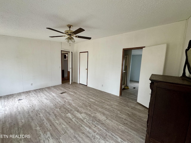 unfurnished bedroom with a textured ceiling, a ceiling fan, and wood finished floors