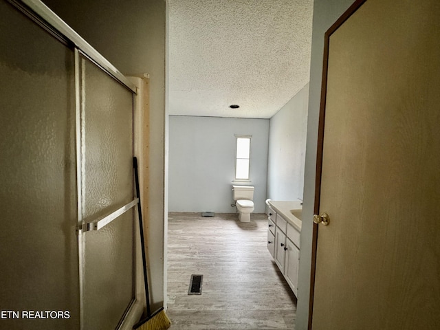 bathroom with visible vents, toilet, wood finished floors, a textured ceiling, and vanity