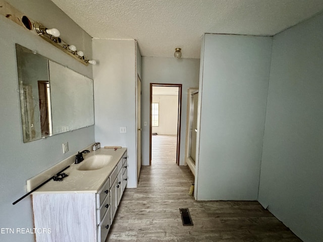 bathroom with a textured ceiling, wood finished floors, and vanity