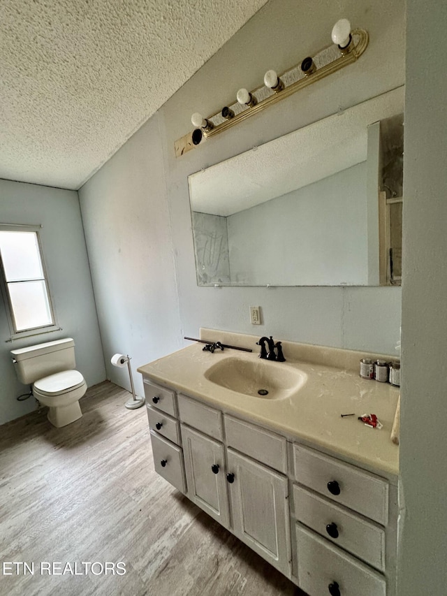 bathroom featuring toilet, a textured ceiling, wood finished floors, and vanity