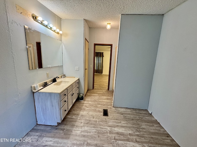 bathroom featuring wood finished floors, a textured ceiling, vanity, and visible vents