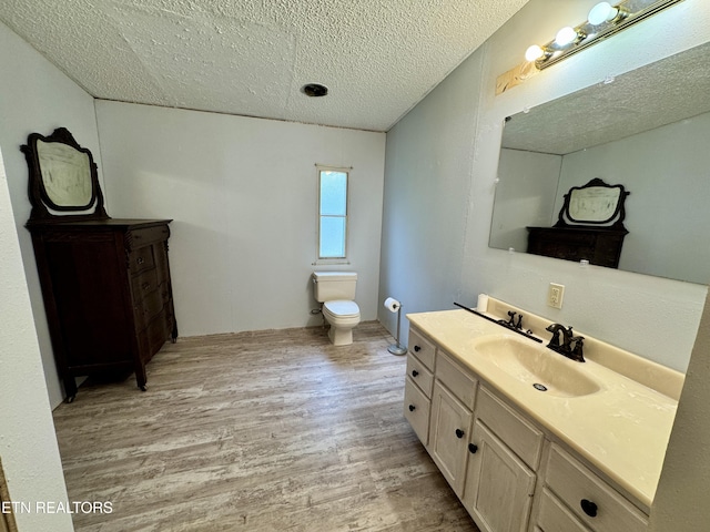 bathroom featuring wood finished floors, a textured ceiling, toilet, and vanity