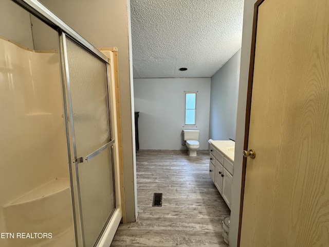 full bath with a shower stall, wood finished floors, a textured ceiling, toilet, and visible vents