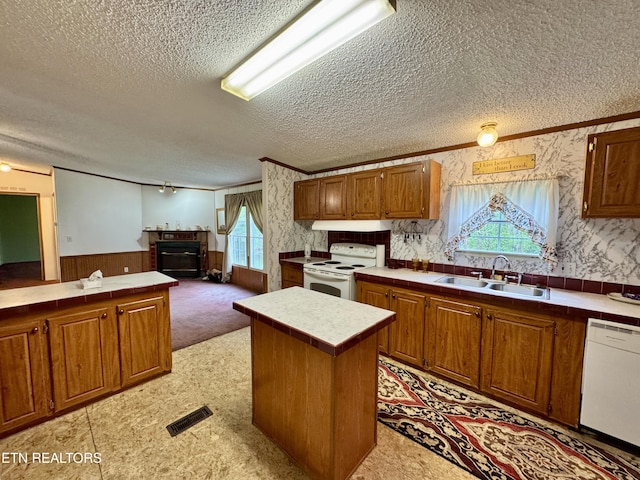 kitchen with a sink, a textured ceiling, visible vents, a glass covered fireplace, and white appliances