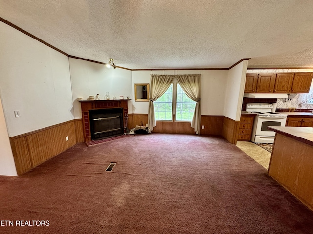 unfurnished living room with a glass covered fireplace, a textured ceiling, crown molding, and wainscoting