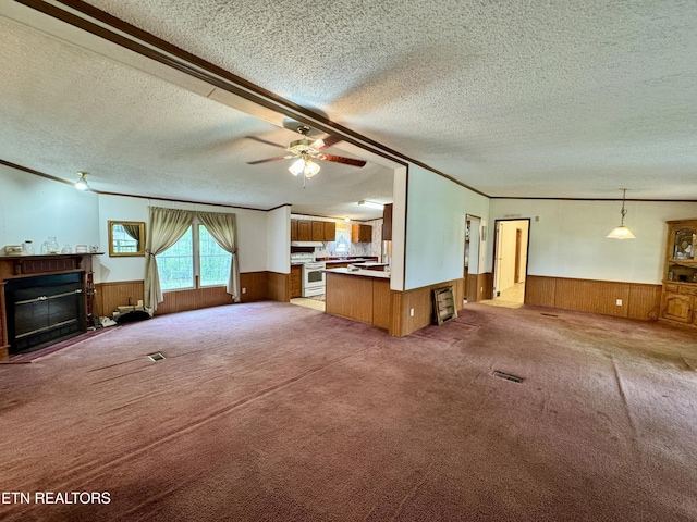 unfurnished living room featuring a glass covered fireplace, a textured ceiling, and wainscoting