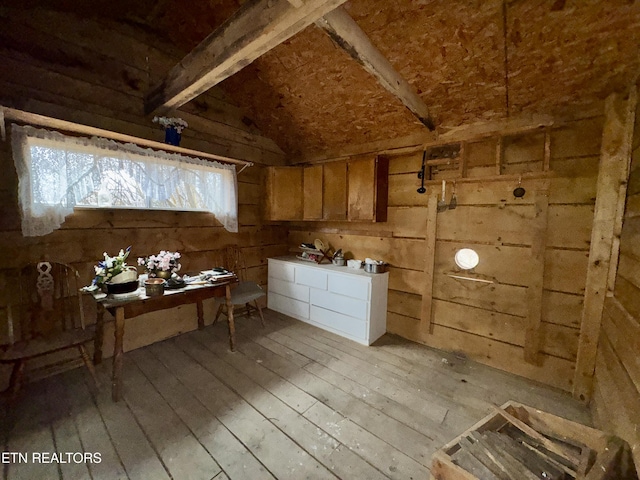 miscellaneous room featuring light wood-style flooring, wooden walls, and vaulted ceiling