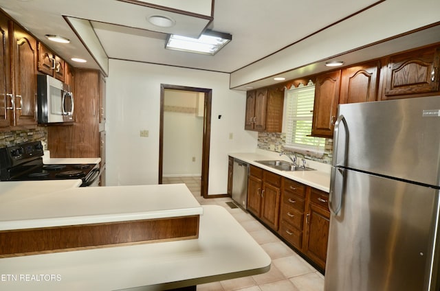 kitchen featuring light tile patterned floors, stainless steel appliances, a sink, light countertops, and tasteful backsplash