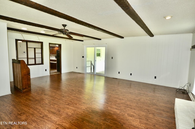 unfurnished living room featuring a textured ceiling, a ceiling fan, wood finished floors, and beamed ceiling