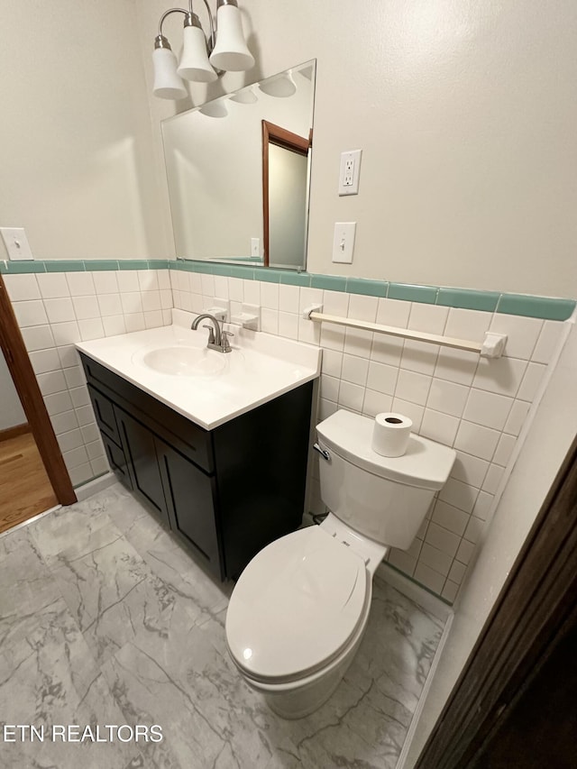 bathroom featuring marble finish floor, a wainscoted wall, vanity, and toilet