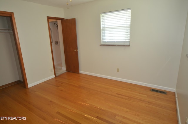 unfurnished bedroom featuring light wood-type flooring, baseboards, and a closet