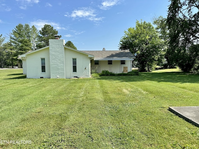 rear view of property featuring a lawn and a chimney