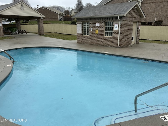 community pool featuring a patio area, fence, and an outdoor structure