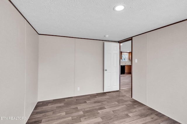 spare room featuring ornamental molding, a textured ceiling, and wood finished floors