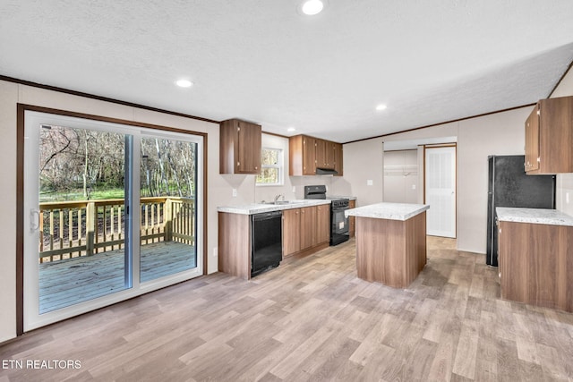 kitchen featuring light wood-style flooring, light countertops, ornamental molding, a center island, and black appliances