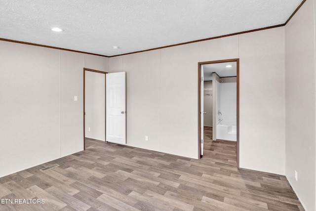 spare room with a textured ceiling, ornamental molding, and wood finished floors