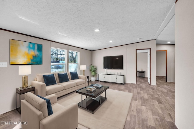 living room featuring a textured ceiling, ornamental molding, wood finished floors, and recessed lighting