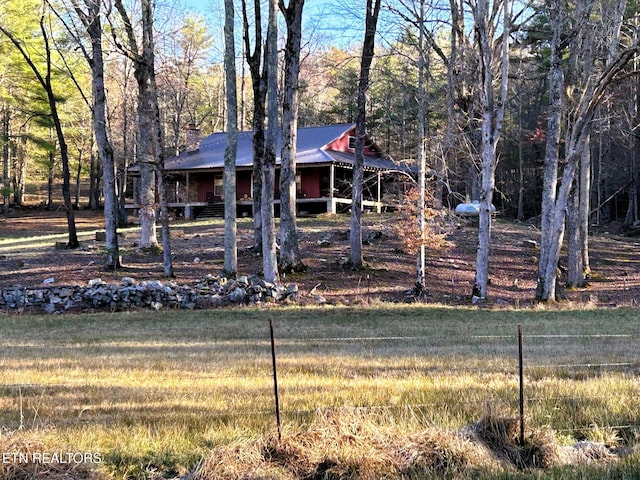 view of front of house featuring a view of trees, a chimney, and metal roof