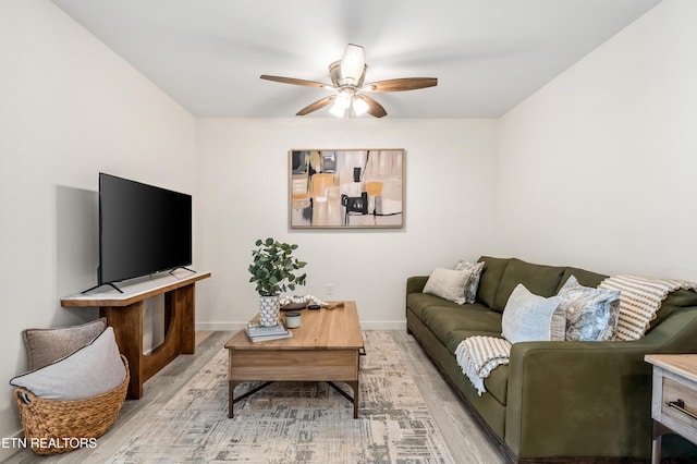 living room with light wood-type flooring, baseboards, and a ceiling fan