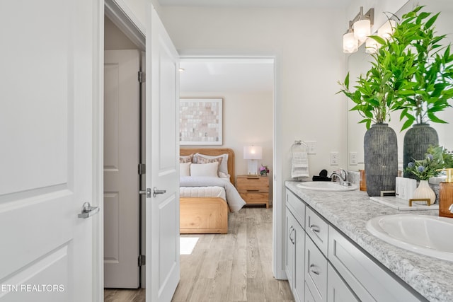 ensuite bathroom with a sink, ensuite bathroom, wood finished floors, and double vanity